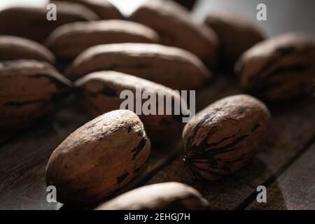 Eine Makroaufnahme mit selektivem Fokus auf eine Handvoll Pekannüsse in Schalen auf einem Holztisch. Stockfoto