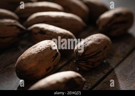 Eine Makroaufnahme mit selektivem Fokus auf eine Handvoll Pekannüsse in Schalen auf einem Holztisch. Stockfoto