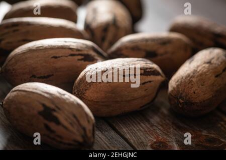 Eine Makroaufnahme mit selektivem Fokus auf eine Handvoll Pekannüsse in Schalen auf einem Holztisch. Stockfoto