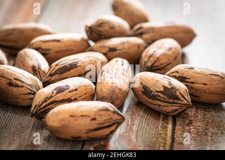 Eine Makroaufnahme mit selektivem Fokus auf eine Handvoll Pekannüsse in Schalen auf einem Holztisch. Stockfoto