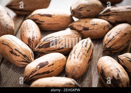 Eine Makroaufnahme mit selektivem Fokus auf eine Handvoll Pekannüsse in Schalen auf einem Holztisch. Stockfoto