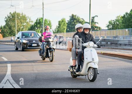 Ein älteres Paar, das in der Stadt auf dem Motorrad unterwegs ist. Motorradfahrer fahren Motorrad und Autos auf der Straße. Mailand, Italien - 26. Mai 2020 Stockfoto