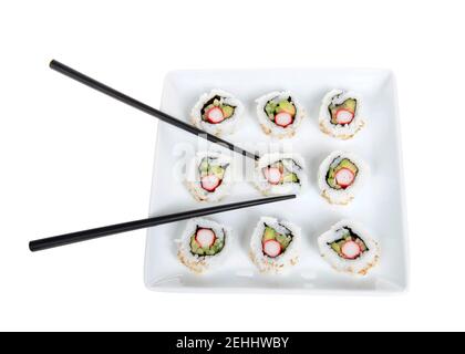 Nahaufnahme von oben Ansicht von Kalifornien rollt Sushi auf einem großen quadratischen Porzellanteller mit schwarzen Stöcken. Isoliert auf Weiß. Stockfoto