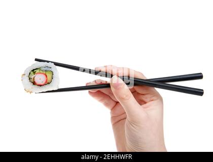 Nahaufnahme der weiblichen kaukasischen Hand mit schwarzen Stöcken mit einem kalifornischen Sushi-Brötchen, isoliert auf Weiß. Stockfoto