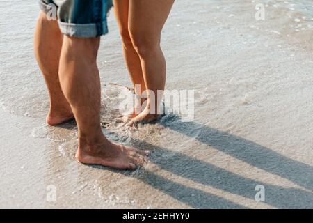 Die Beine des Paares stehen zusammen am Strand. Mann und Frau in der Liebe. Stockfoto