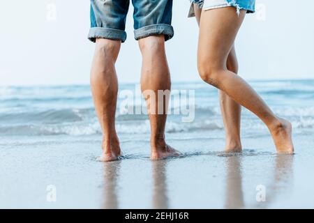 Die Beine des Paares stehen zusammen am Strand. Mann und Frau in der Liebe. Stockfoto