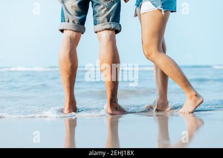 Die Beine des Paares stehen zusammen am Strand. Mann und Frau in der Liebe. Stockfoto