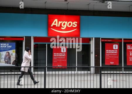 London, Großbritannien. Februar 2021, 19th. Eine Frau, die mit dem Handy kommuniziert, geht an einer Zweigstelle von Argos in London vorbei. Nicht wesentliche Einzelhandelsgeschäfte sind derzeit während der nationalen Sperre geschlossen. Kredit: SOPA Images Limited/Alamy Live Nachrichten Stockfoto