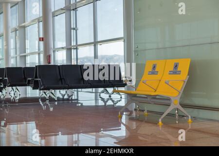 Leere Priority-Sitzplätze am internationalen Flughafen für Behinderte reserviert. Normale und gelbe Behindertensitze im Wartebereich vor dem Einsteigen. Stockfoto