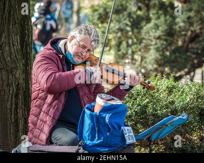 Bukarest, Rumänien - 02,12.2021: Straßenkünstler beim Geigenspielen im Cismigiu Park, Bukarest. Stockfoto