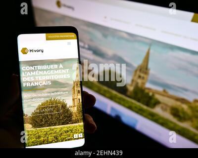 Person, die Smartphone mit Website und Logo der französischen Telekom-Tower-Firma Hivory auf dem Bildschirm hält. Konzentrieren Sie sich auf die Mitte der Anzeige des Mobiltelefons. Stockfoto