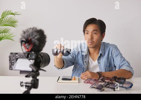 Asiatische Vlogger oder Blogger zeigen schwarze Mode-Brille mit Kunden vor der Kamera und Aufnahme von Video. Freelancer Online Live Streaming mit Custom Stockfoto