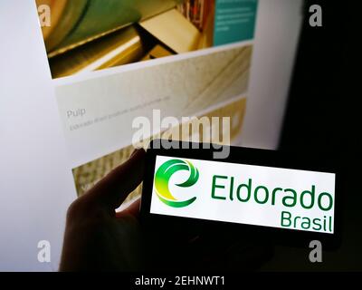 Person hält Handy mit Logo des brasilianischen Zellstoff-Hersteller Eldorado Brasil Celulose SA auf dem Bildschirm mit Webseite. Fokus auf Handy-Display. Stockfoto