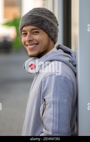 Lächelnder junger latein-Mann-Sporttraining mit Kopfhörern im Hochformat Im Freien Stockfoto