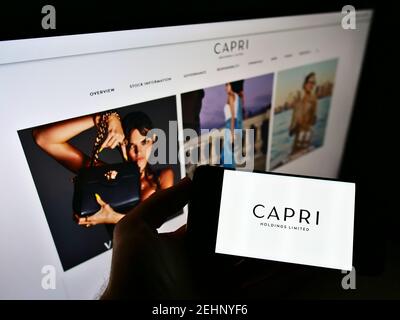 High-Angle-Ansicht der Person hält Smartphone mit Logo des Modeunternehmens Capri Holdings Limited auf dem Bildschirm mit Webseite. Fokus auf Handy-Display. Stockfoto