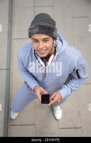 Musik hören lächelnd junge lateinische Mann Läufer Porträt-Format Sporttraining von oben im Freien Stockfoto
