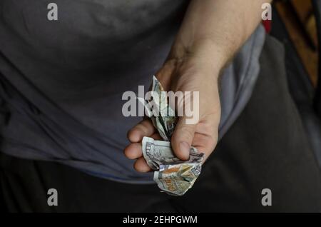 Eine Hand hält zerknittertes Geld. Ein erwachsener Mann hält zweihundert Dollarscheine in seiner linken Hand fest. Blick von oben aus einem Winkel. Selektiver Fokus. Stockfoto