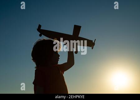 Kinderträume. Junge Pilot mit Spielzeug Flugzeug, Silhouette. Kinder spielen im Freien. Frohe Kindheit. Tagträumen. Stockfoto