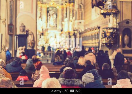 Menschen während einer Predigt in einer katholischen Kirche. Getönt. Ausgewählter Fokus Stockfoto
