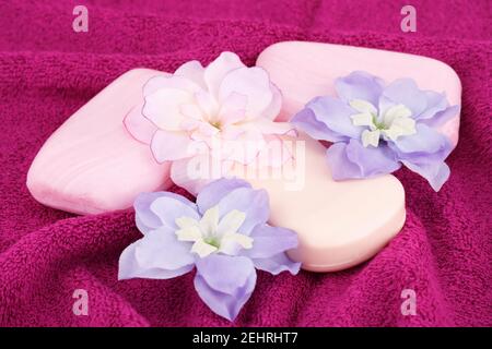 Bunte Seifen und Blumen auf rosa Handtuch. Stockfoto