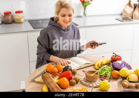 Frau mit Kalorienzähler Anwendung auf ihrem Smartphone Stockfoto