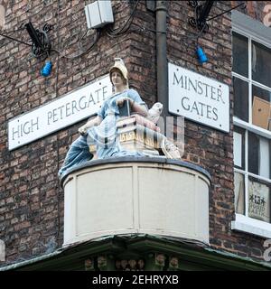 YORK, Großbritannien - 13. MÄRZ 2010: Ungewöhnliches Straßenschild für Minster Gates und High Petergate mit Statue von Minerva, Göttin der Weisheit mit Eule und Büchern Stockfoto