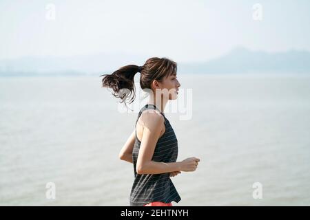 Junge asiatische Frau Läuferin läuft am Meer, schwarz und weiß Stockfoto