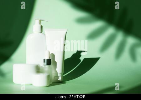 Set von kosmetischen Flasche Creme Glas, Gel, Lotion auf grünem Hintergrund mit tiefen Blättern Schatten. Beauty-Produkt Nachbau Paket, weiße Kunststoff-Behälter Stockfoto