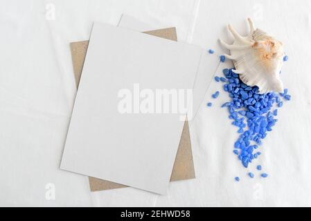 Modische Stock Schreibwaren Hintergrund - weiße Karte und Muscheln auf einem weißen Tisch. Romantischer Hintergrund. Leer für eine Einladungskarte. Stockfoto