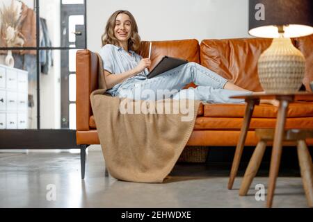 Frau, die von zu Hause aus mit einem digitalen Tablet auf dem Sofa arbeitet Stockfoto