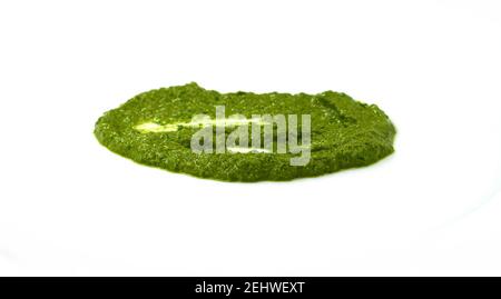 Pesto verbreiten oder Blob in einer Schüssel isoliert auf weißem Hintergrund. Grüne italienische hausgemachte verschüttete Sauce aus gemahlenem Basilikum, Knoblauch, Pinienkernen, Oliven. Stockfoto