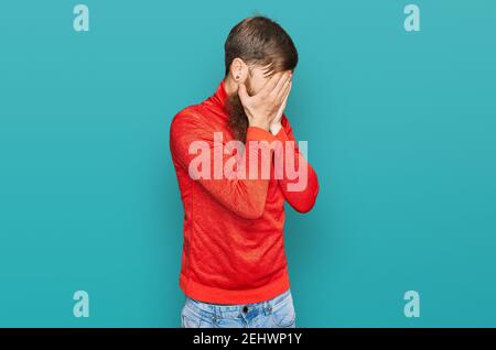 Rotschopf Mann mit langen Bart tragen lässige Kleidung mit trauriger Ausdruck Abdeckung Gesicht mit Händen beim Weinen. Depression Konzept. Stockfoto