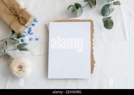 Layout-Szene eines Schreibwarenlayouts. Leere vertikale Grußkarte aus Kraftpapier. Draufsicht leer für Einladung Stockfoto