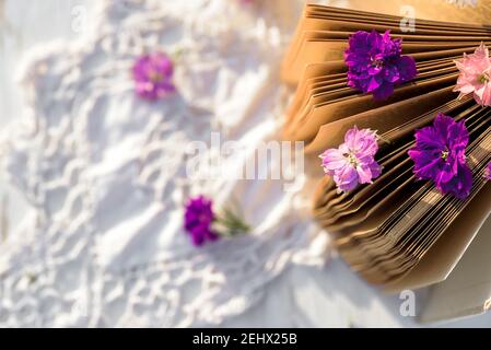 Violette Blumen auf einem Buch. Durchbrochene gestrickte Tischdecke auf einem alten Holztisch. Abend im Dorf. Sonnenuntergang im Freien, Batanica, schöne Blumen Stockfoto