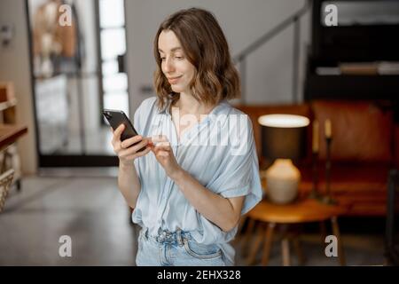 Frau mit Smartphone im Wohnzimmer Stockfoto