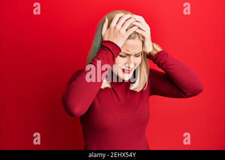 Junge blonde Frau trägt Freizeitkleidung leiden unter Kopfschmerzen verzweifelt und gestresst, weil Schmerzen und Migräne. Hände auf dem Kopf. Stockfoto