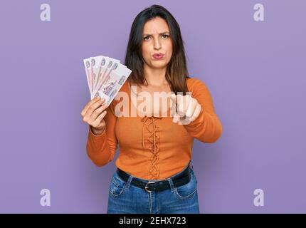 Schöne hispanische Frau hält russische 500 Rubel Banknoten zeigen mit dem Finger auf die Kamera und Sie, selbstbewusste Geste suchen ernst Stockfoto