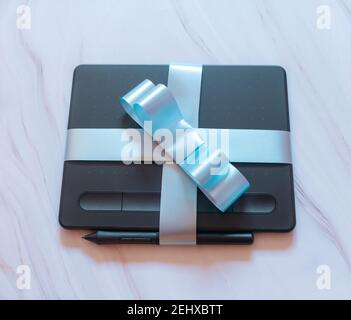 Digitales Tablet mit blauer Schleife auf Marmorboden Stockfoto