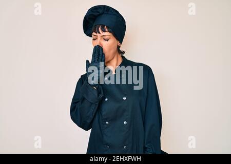 Schöne brunettte Frau trägt professionelle Koch Uniform gelangweilt Gähnen müde Abdeckung Mund mit der Hand. Unruhig und Schläfrigkeit. Stockfoto