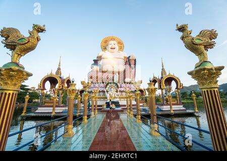 KOH SAMUI, THAILAND - 10. Januar 2020: Mann mit Kamera steht auf einer Brücke zu einer riesigen, farbenfrohen buddha-Statue am Wat Plai laem-Tempel auf koh samui Stockfoto