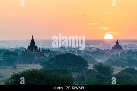 Nebliger, farbenfroher Sonnenaufgang über den Ebenen der archäologischen Stätte Bagan in myanmar (Burma). Stockfoto
