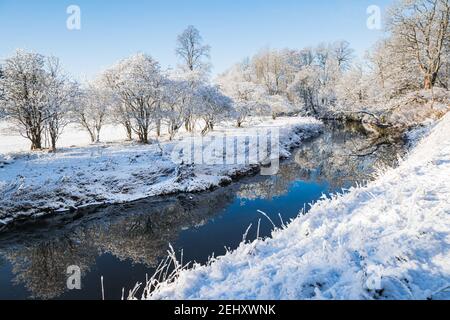 Winter im Pollok Country Park, Glasgow, Schottland, mit schneebedeckten Bäumen, die sich im Fluss spiegeln. Stockfoto