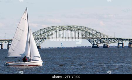 Segelboot mit der Great South Bay Brücke im Hintergrund und dem Wasserturm auf Fire Island im Blick. Stockfoto