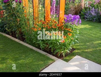 Kleiner englischer Garten - Rasengras mit Blumenbeeten gefüllt mit Pflanzen von bunten Blumen Blumenbeete einschließlich Helenium - Dahlien England GB Großbritannien Stockfoto