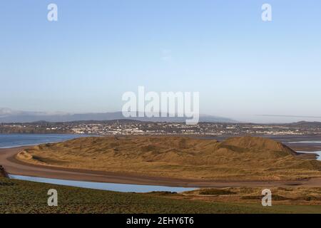 Grassdüne mit irischer Stadt und wolkigen Bergen im Hintergrund. Platz kopieren. Tramore. Waterford. Irland. Stockfoto