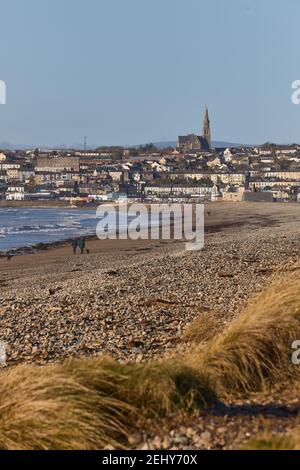 Irischer Strand mit Stadt im Hintergrund mit katholischer Kirche auf dem Berg. Tramore Naturschutzgebiet. Waterford. Irland. Vertikales Format Stockfoto