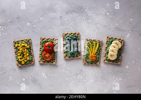 Hausgemachte Sandwiches mit Tomaten, Banane, Heidelbeere, Mais, Pfeffer, Chlorella, Spirulina und Käse auf Roggen Vollkorn Toastbrot. Sandwiches auf Cutti Stockfoto