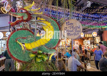 Detail am Eingang des berühmten Ben Thanh Street Food Market in Ho Chi Minh City in der Nacht, mit Menschen essen im Hintergrund Stockfoto