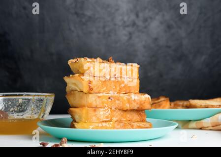 Hausgemachter französischer Toast gebraten mit Honig auf einem blauen Teller auf einem dunklen Hintergrund. Eingeweicht in Milch Ei Mischung. Gesundes Frühstück. Stockfoto