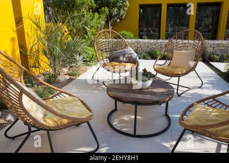 Arbeiten von zu Hause Gartenbüro Studio mediterranes Klima Garten modern grau gepflastert Stein Terrasse Rattan Gartenmöbel Tischstühle UK Stockfoto